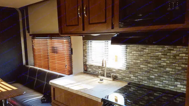 RV rental interior: Sunny kitchen, dinette, and backsplash with a sink, stove, and microwave under bright windows.. Forest River Salem Cruise Lite 2017