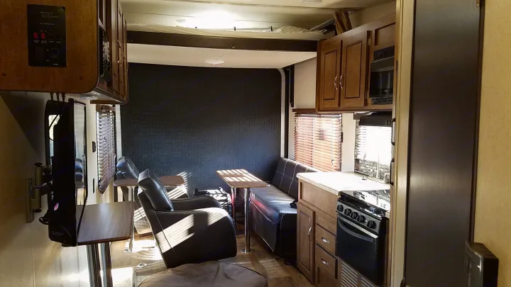 Spacious RV rental interior showing a kitchen, dining area with recliners & sofa, and an overhead bunk bed.. Forest River Salem Cruise Lite 2017