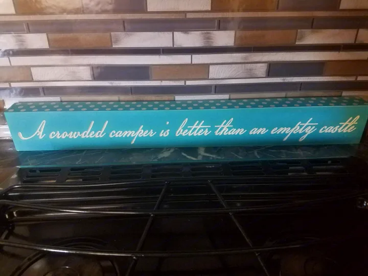 Teal sign on a stovetop: "A crowded camper is better than an empty castle." Great for RV rental adventures!. Keystone RV Springdale 2017