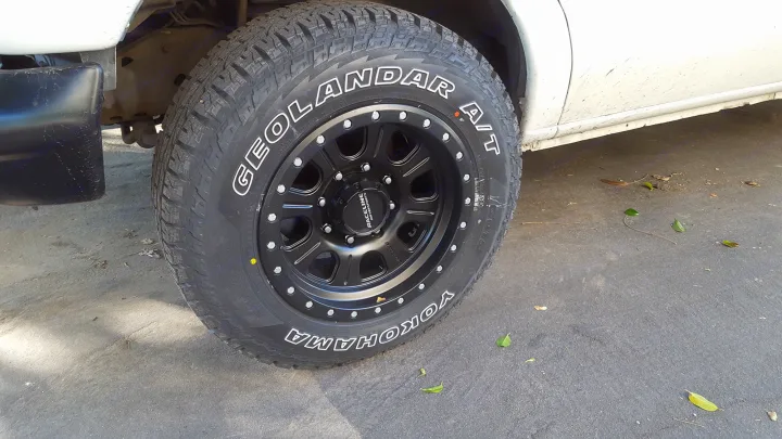 A pristine Yokohama GEOLANDAR A/T tire and black Raceline wheel on an RV rental, ready for any adventure.. Ford E350 2000
