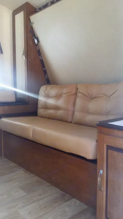 Comfortable tan sofa in an RV rental, possibly converts to a bed. Ideal for relaxing after travel.. Forest River Salem Cruise Lite 2018
