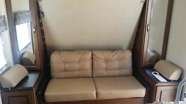 Plush beige sofa with bolster pillows & compact cabinetry in RV rental interior, ready for your trip.. Forest River Salem Cruise Lite 2018