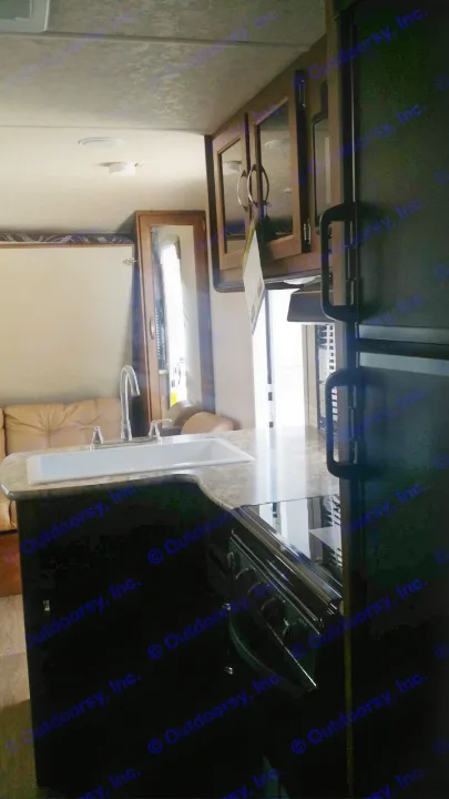 Spacious RV rental interior featuring a kitchen with sink, counters, and a large refrigerator, plus a cozy living area.. Forest River Salem Cruise Lite 2018