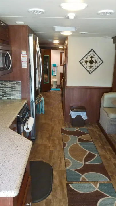 RV rental interior showing kitchen, living area with seating, and a hallway leading to the bathroom. Neutral tones throughout.. Forest River Georgetown 2017