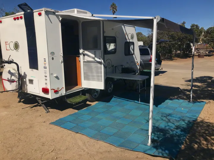 Experience eco-friendly camping with this ECO Skamper rv rental, featuring an extended awning and outdoor setup at a sunny campsite.. Dutchman Eco 2010