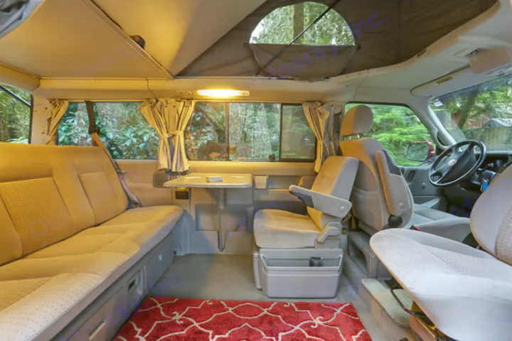 Inviting RV rental camper van interior: pop-top roof, convertible seating, table, and swiveling front seats.. Volkswagen Eurovan weekender 2003