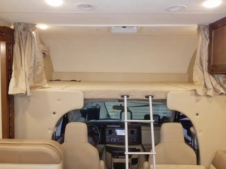 Interior of an RV rental: features a cozy cab-over bed with ladder above the driver's cockpit.. Thor Motor Coach Freedom Elite 2018