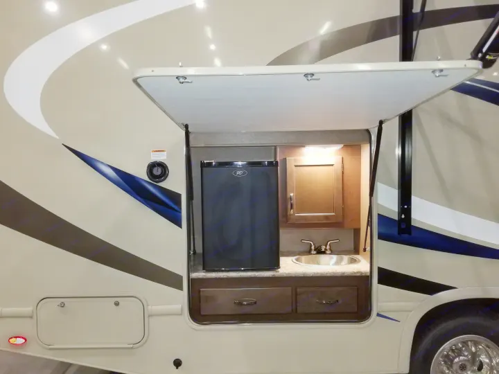 Experience convenience with this RV rental's exterior kitchen: a compact fridge, sink, and storage built into the side hatch.. Thor Motor Coach Freedom Elite 2018