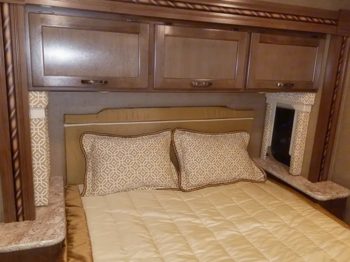 Comfortable RV bedroom featuring overhead cabinets, bed, and side tables. Ideal for an RV rental stay.. Thor Motor Coach Freedom Elite 2018