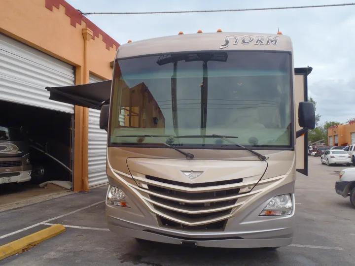 Front view of a modern RV rental, a 'Storm' motorhome, parked. Its awning is extended, ideal for travel.. Fleetwood Storm 2015