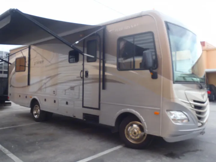 RV rental: A beige and grey Fleetwood Storm motorhome with an extended awning, parked on asphalt pavement.. Fleetwood Storm 2015