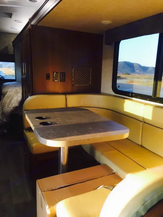 Bright RV rental interior: dinette with U-shaped seating, table, outdoor view, and bedroom access.. Mercedes Benz Forest River Forester 2017