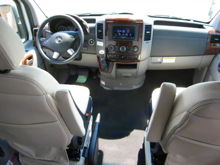 Spacious RV rental cabin view: light-colored front seats with armrests, Mercedes steering wheel, and modern dashboard.. Airstream Interstate 2014