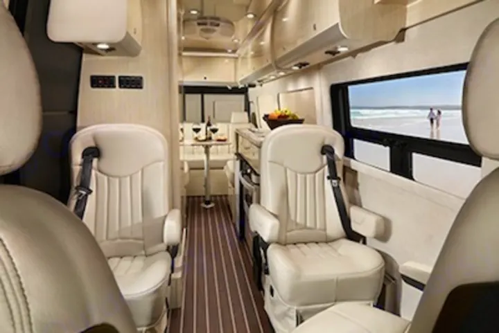 Step inside this luxury RV rental featuring plush seating, a well-equipped kitchen, and a scenic window view.. Airstream Interstate 2014