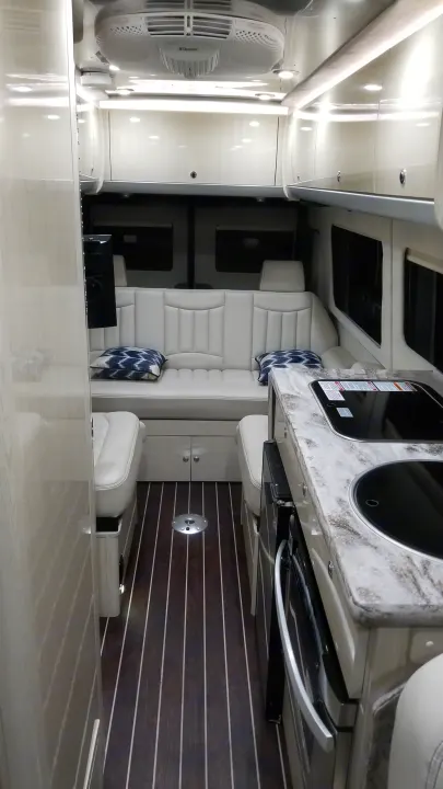 Pristine luxury RV rental interior: modern kitchenette, plush seating, and elegant wood paneling offer premium comfort for travel.. Airstream Interstate 2014
