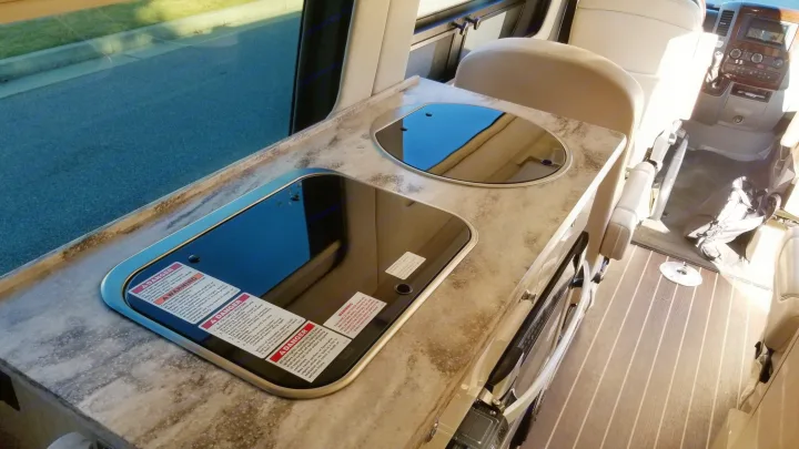 RV rental kitchen area. Modern camper van interior featuring a sleek countertop with covered stovetop and sink. Warnings.. Airstream Interstate 2014