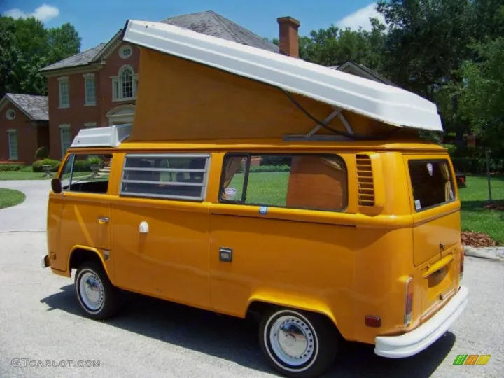 Bright yellow vintage VW camper van with raised pop-top roof, parked in a driveway. Perfect for your next rv rental trip!. Volkswagen Westfalia 1977