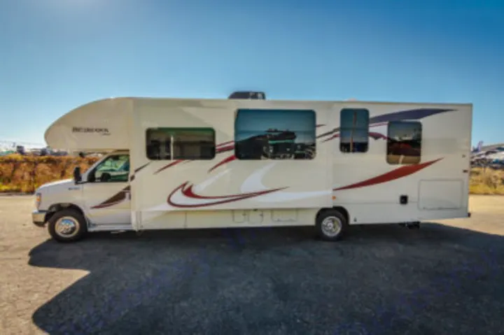 This spacious beige RV rental is parked on asphalt, ready for your next road trip adventure.. Jayco Redhawk 2016