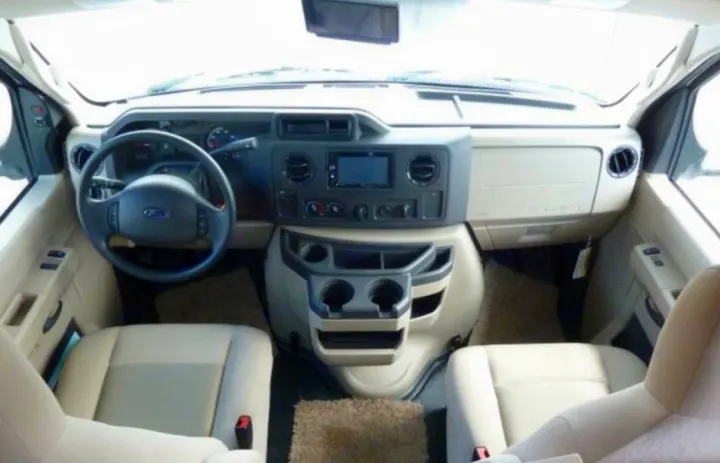 Spacious Ford RV rental cockpit view: beige interior, steering wheel, dashboard with infotainment screen, and comfy front seats.. Forest River Sunseeker 2017