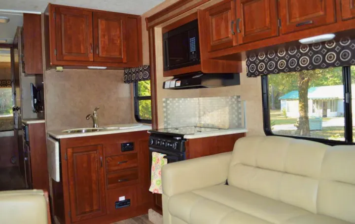 This RV rental offers a bright interior with a full kitchen (sink, stove, microwave) and a comfortable cream sofa.. Forest River Sunseeker 2017