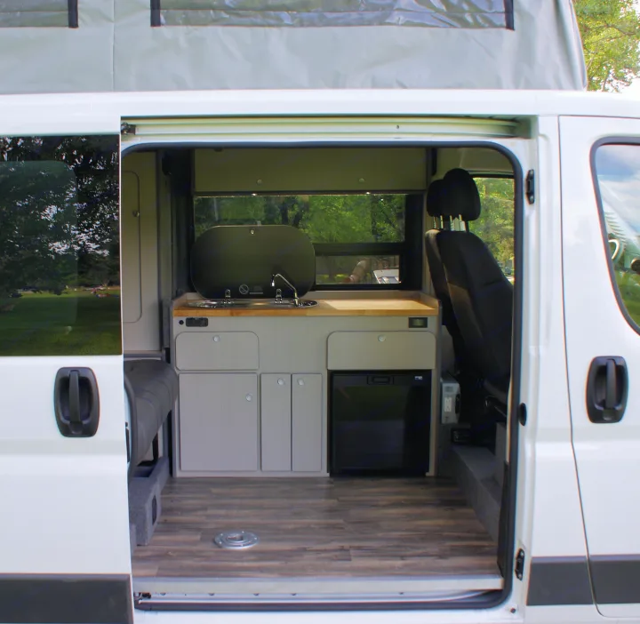 Spacious rv rental camper van interior with kitchenette, fridge, and pop-top roof, ready for your next adventure.. Dodge Promaster 2017