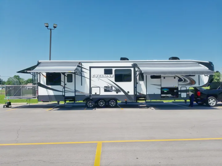 Spacious white Cyclone fifth wheel RV rental with extended awnings and black pickup truck, ready for your next adventure.. Heartland Cyclone 2014