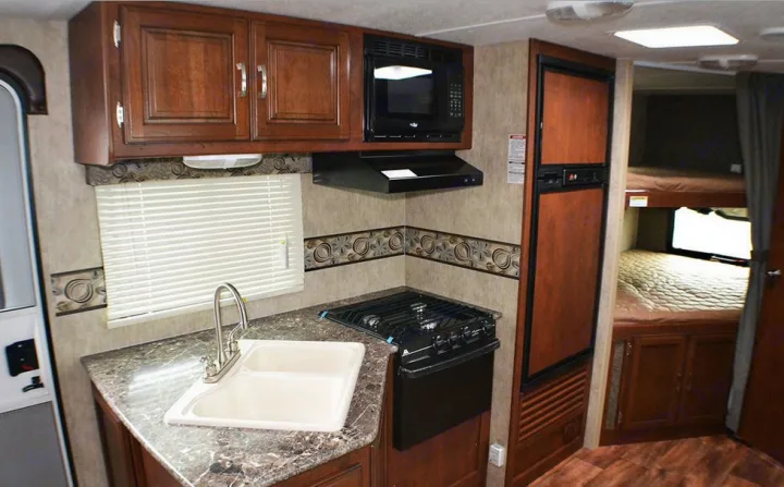 Spacious RV rental interior with full kitchen, microwave, stove, sink, fridge, and bunk beds. Perfect for family adventures.. Passport BHS 2015
