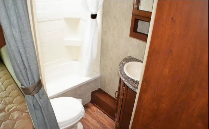Compact RV rental bathroom featuring a shower/tub, toilet, and vanity with sink, designed for efficient space use.. Passport BHS 2015