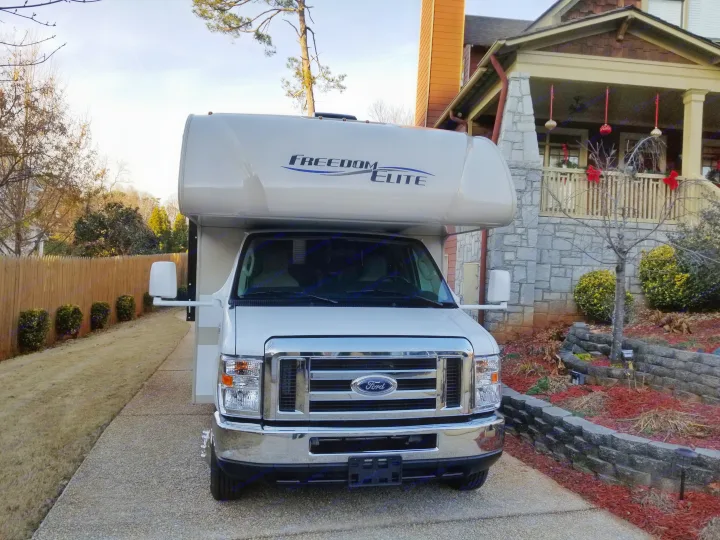 Front view of a white Freedom Elite motorhome parked in a driveway, ready for an RV rental.. Thor Motor Coach Freedom Elite 2018