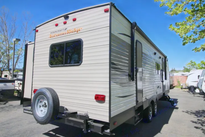 Rear view of a light-colored Starcraft Autumn Ridge travel trailer with a spare tire, ready for RV rental.. Starcraft Autumn Ridge 2017