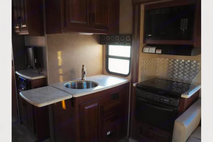 Compact RV rental kitchen with sink, stove, microwave, and convenient fold-out counter. Perfect for travel.. Forest River Sunseeker 2017
