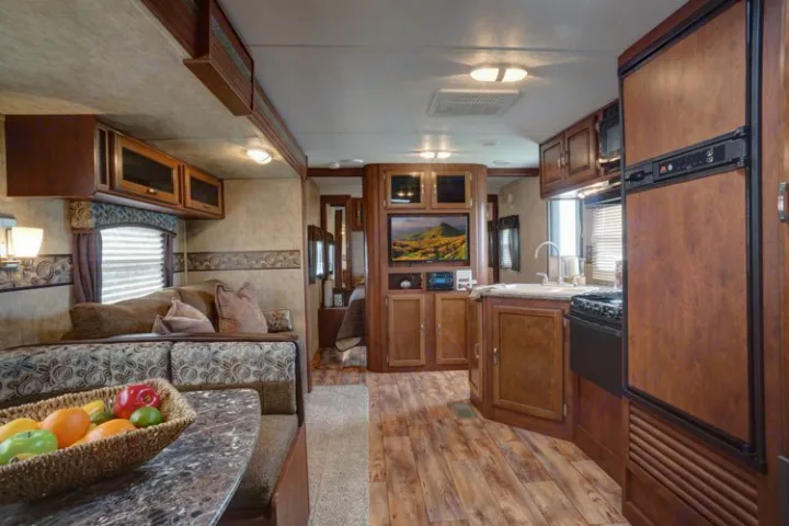 This rv rental showcases a comfortable living area with dining booth, full kitchen, and entertainment system for journeys.. Keystone Passport 2014