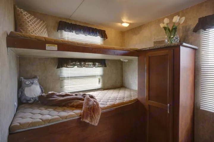 This RV rental bunk bed area offers comfortable sleeping and smart storage, with a cozy, inviting feel.. Keystone Passport 2014