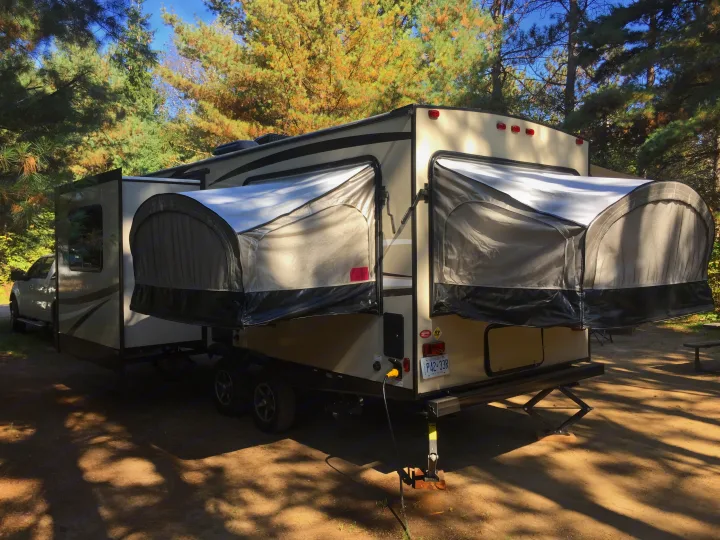 This RV rental, a travel trailer with extended pop-outs, is set up at a sunny campsite. Perfect for outdoor adventures!. Coachmen Freedom Express 2018