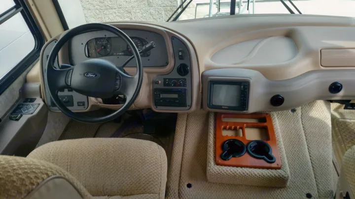 RV rental: Driver's dashboard features a Ford steering wheel, instrument cluster, radio, monitor, and handy cup holders.. National Surf Side 2006