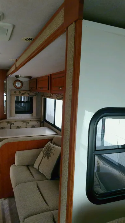 Cozy RV rental interior with dinette, sofa, and wood trim detailing, perfect for comfortable travel.. National Surf Side 2006