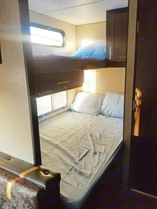 RV rental sleeping area: compact bunk beds with blue linens, bathed in natural light from windows.. grey wolf bunkhouse 2018