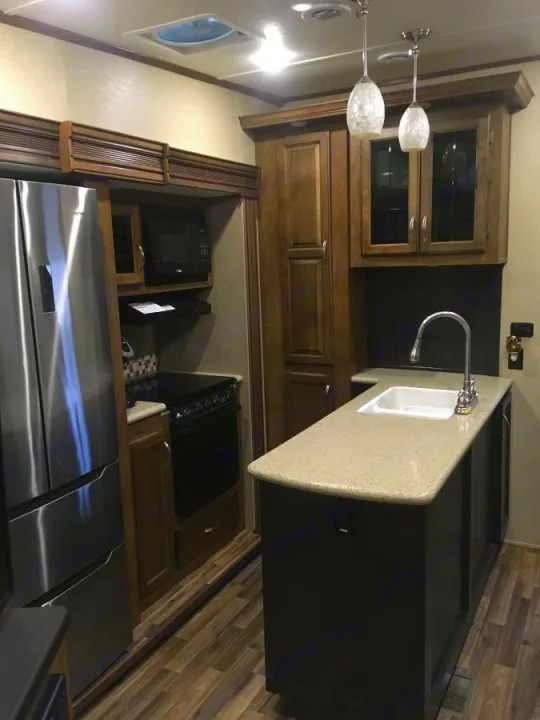 Wonderful kitchen with solid wood cabinets and stainless steel side by side residential fridge with double freezer underneath, double sink, gas oven and range top and microwave.. Coachmen Chaparral 2017
