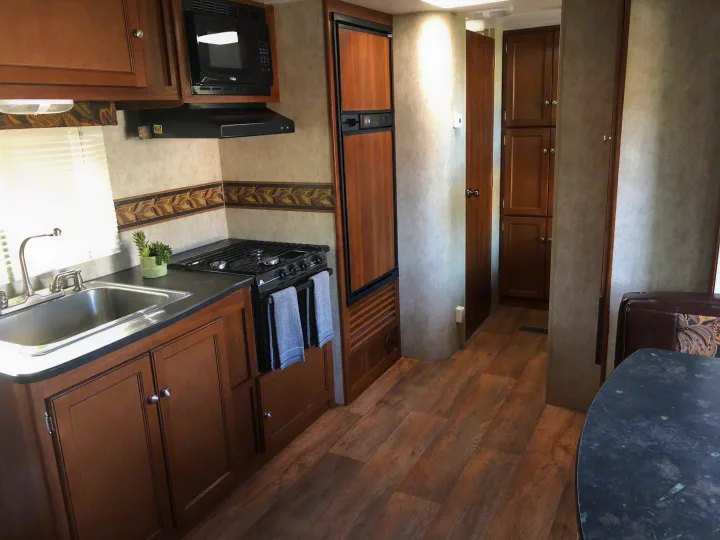 Kitchen area includes a microwave, large refrigerator, gas cooktop, oven and residential style stainless steel sink . Keystone Bullet 2014