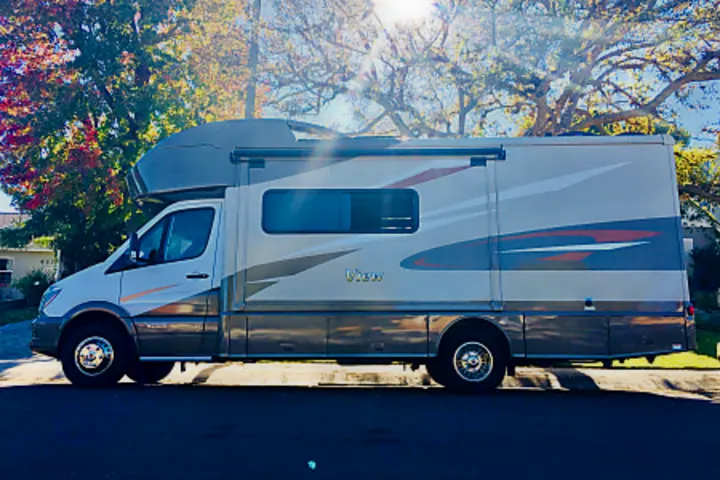 A sleek Class C motorhome, cream with vibrant graphics, ready for your next rv rental adventure. Parked on a sunny street.. Winnebago View 2019