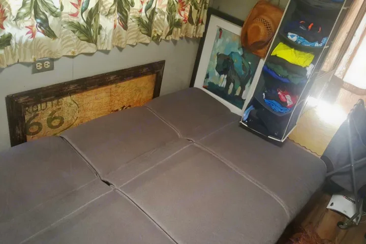 Inside an RV rental: futon bed, Route 66 map, buffalo art, and hanging clothes storage. Compact and ready for adventure.. Clark Cortez 1966
