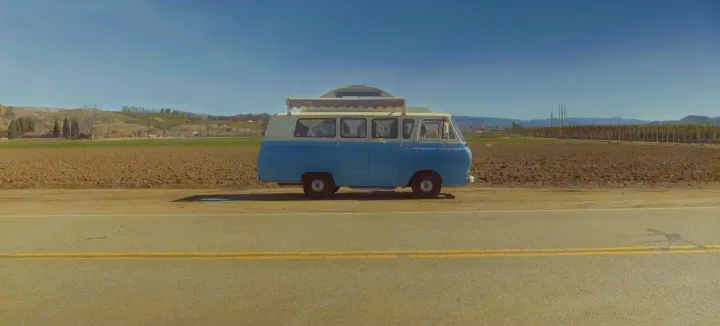 Blue & white vintage RV rental roadside in a scenic valley with fields & mountains under blue sky.. Ford Econoline 1966