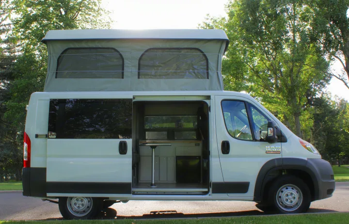 White pop-top camper van, perfect for your next RV rental adventure. Interior visible through open side door.. Dodge Promaster 2017