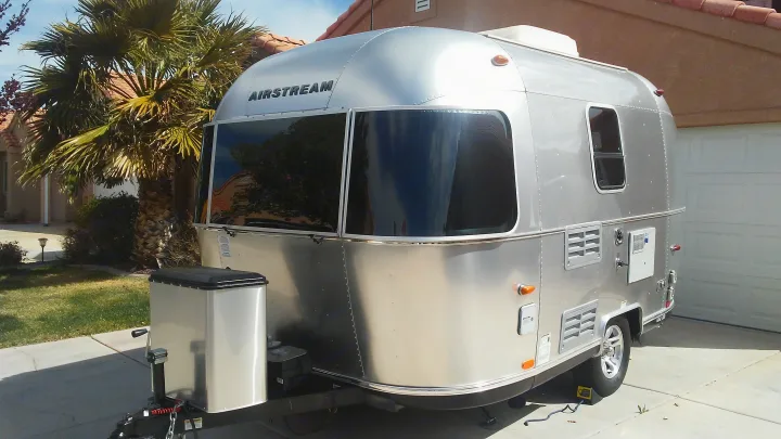 Silver Airstream travel trailer, ideal for an RV rental adventure, parked in a sunny residential driveway.. Airstream Sport 2015