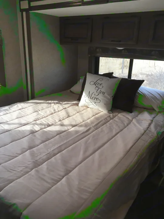 Relaxing RV rental bedroom features a cozy bed with a "Love You More" pillow, overhead storage, and. Coachmen Freelander 2018