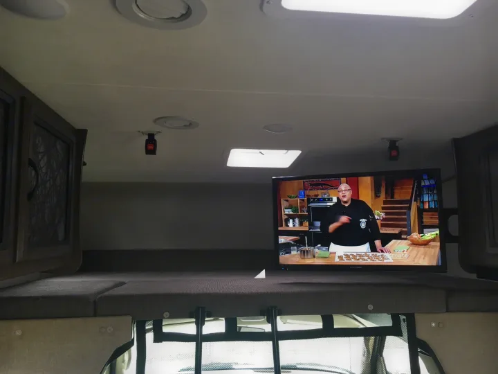 Inside an RV rental, the cab-over bunk offers a TV for entertainment, with ceiling lights,. Coachmen Freelander 2018