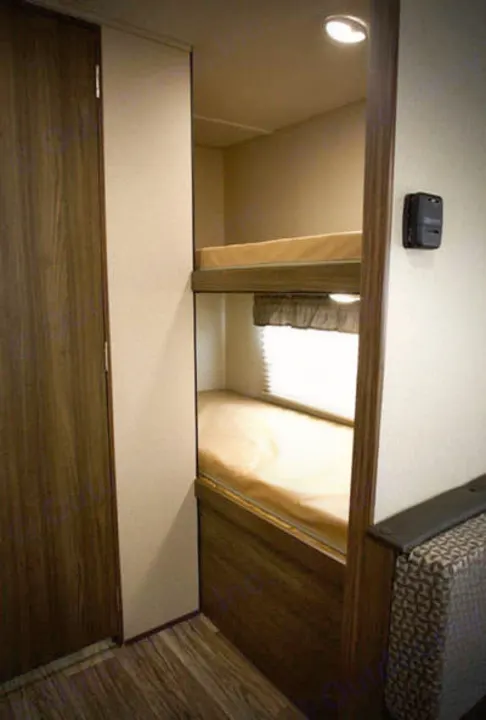 RV rental interior: two stacked bunk beds, window, control panel, and a wooden door for compact living.. Riverside Rv Dream 175BH 2018