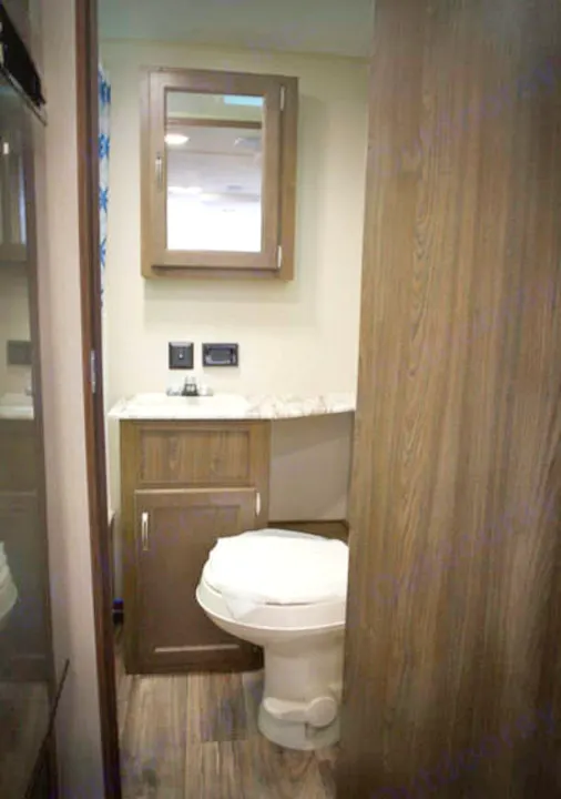 Compact RV rental bathroom with wood-grain vanity, sink, toilet, and medicine cabinet, ideal for travel.. Riverside Rv Dream 175BH 2018