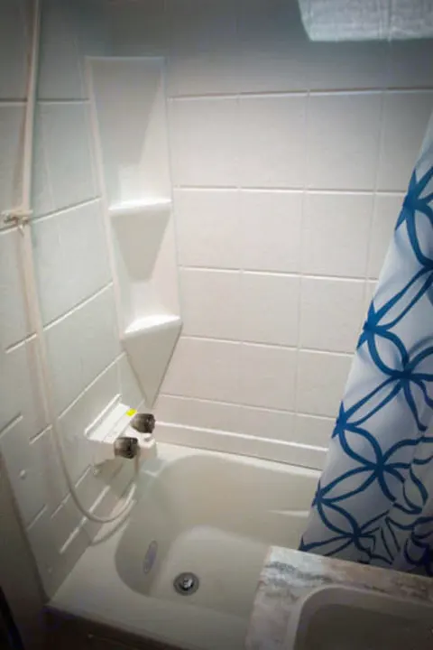 RV rental bathroom featuring a compact tub/shower with white walls and a blue patterned curtain, providing essential travel amenities.. Riverside Rv Dream 175BH 2018