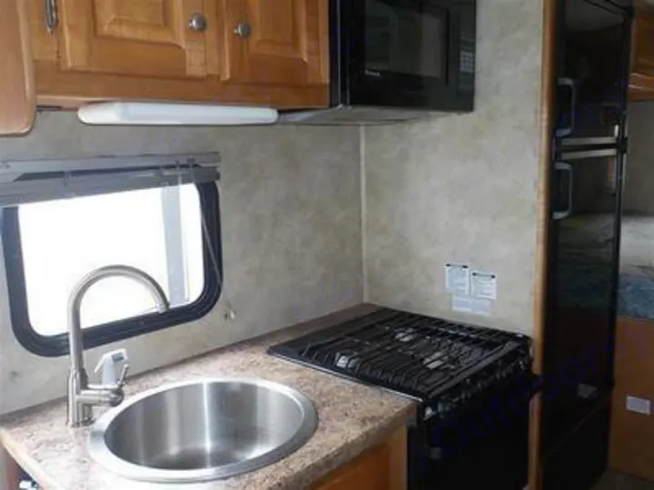 RV rental kitchen: cozy space with sink, window, gas stove, microwave, and fridge, perfect for camping trips.. Gulf Stream Yellowstone 2009